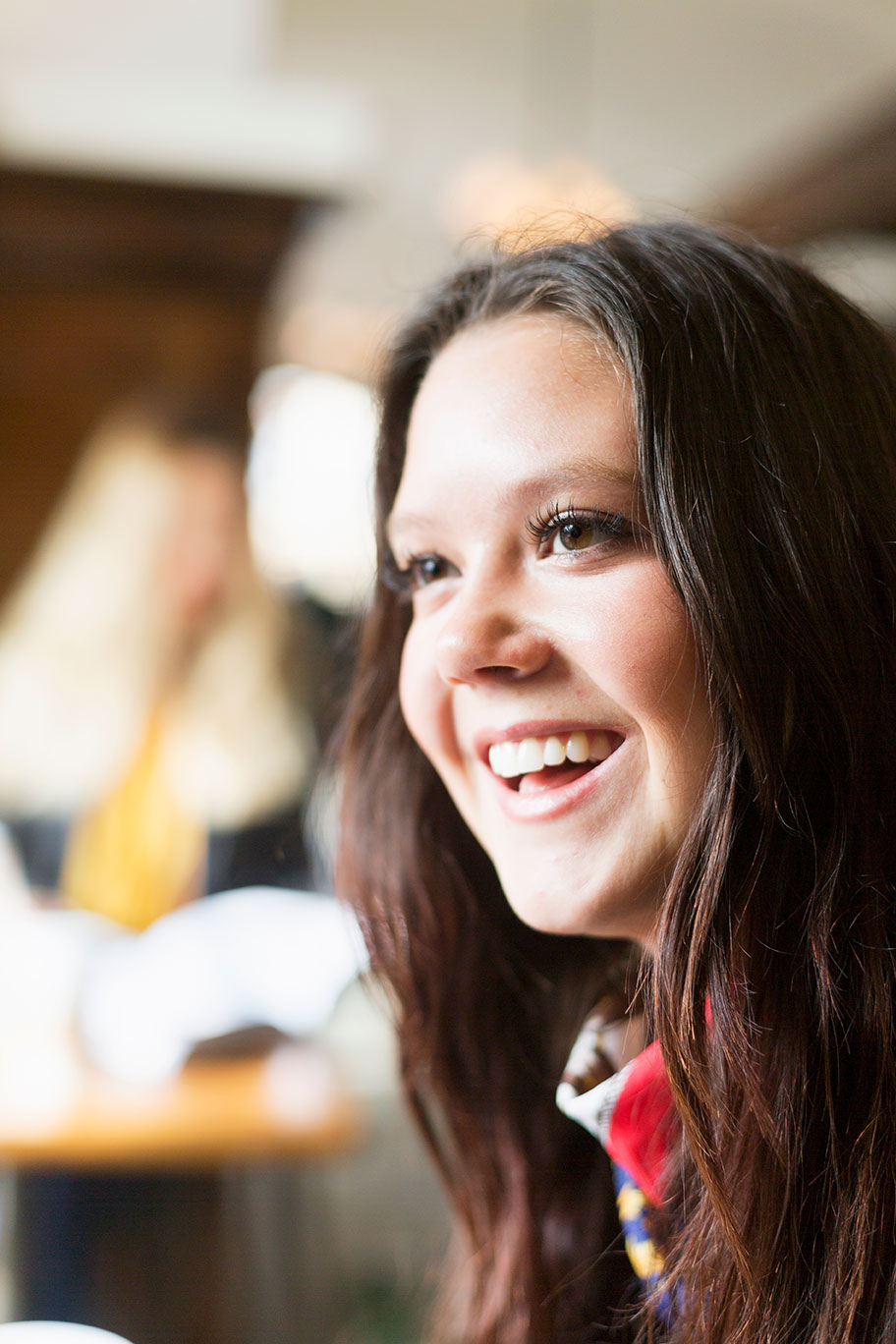 happy young woman looking away in station cafe